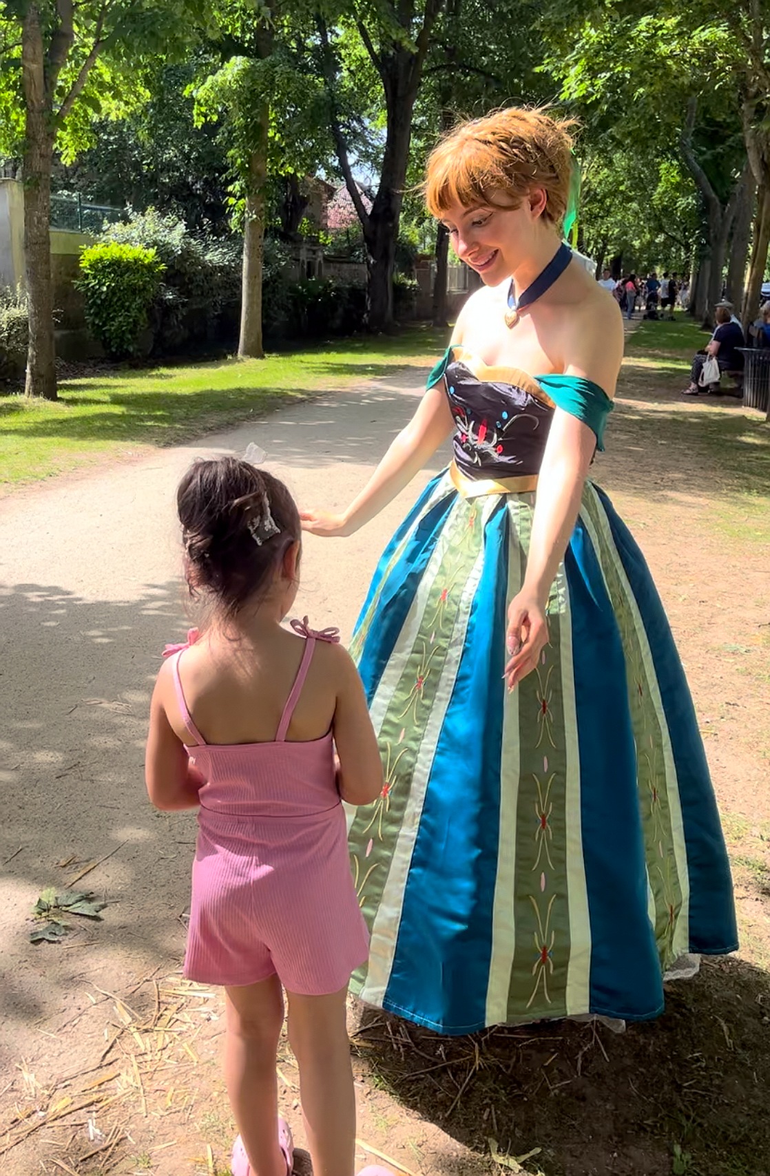 Animatrice costumée en princesse Anna saluant une enfant dans un parc