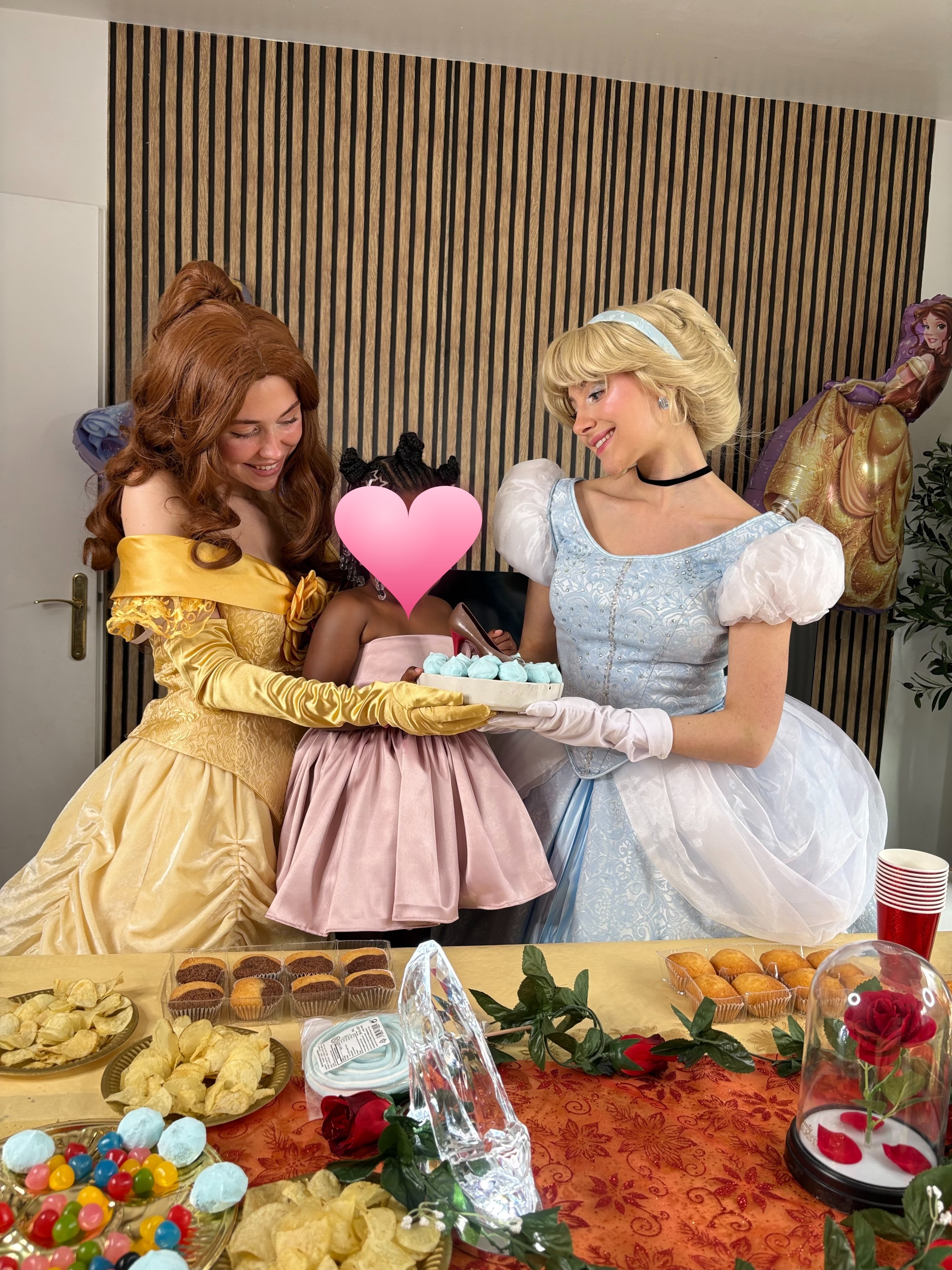 Animatrices costumées en Belle et Cendrillon partageant un gâteau avec une enfant lors d'un goûter d'anniversaire
