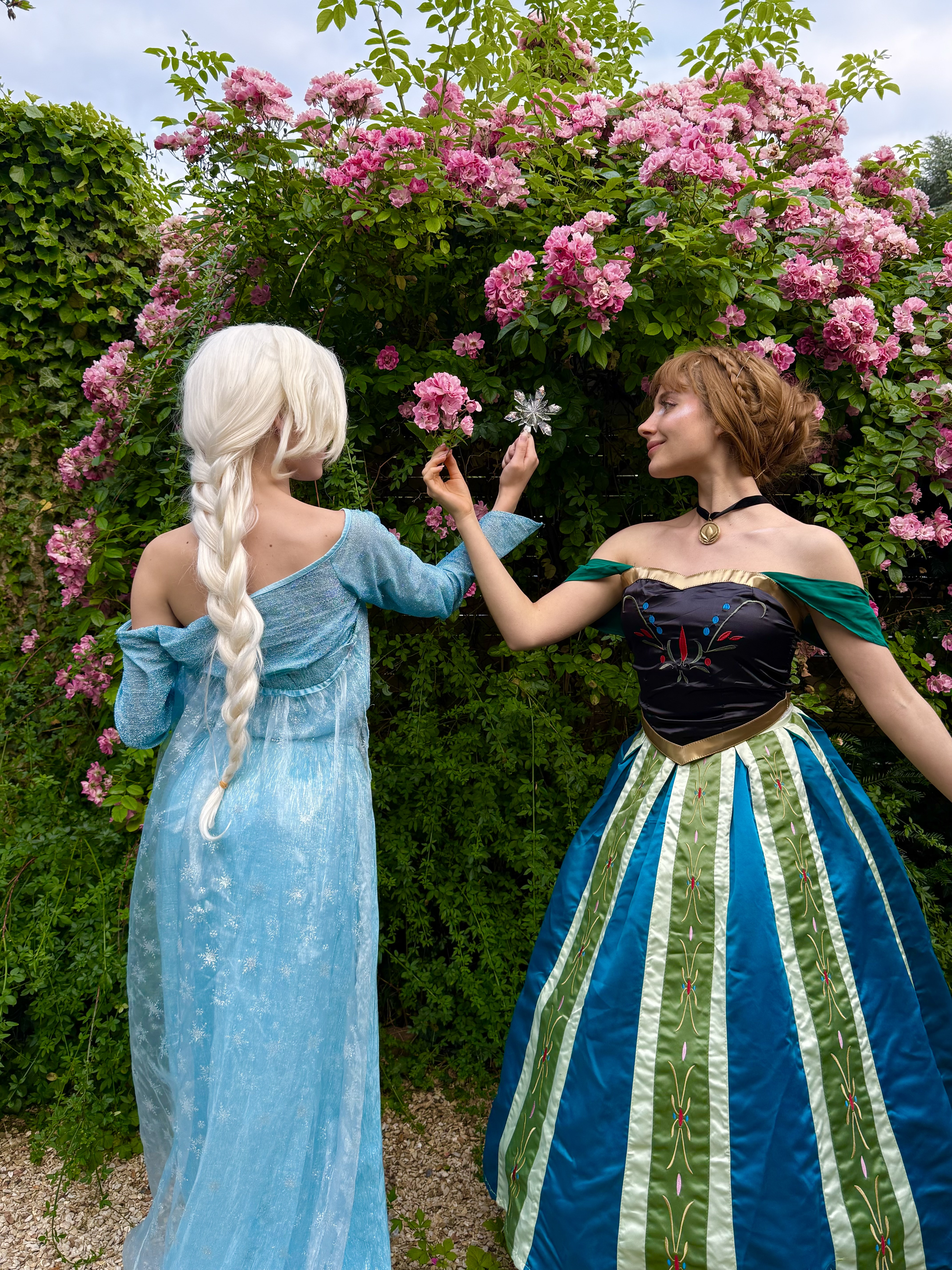 Deux animatrices déguisées en Elsa et Anna (La Reine des Neiges) devant un rosier fleuri, lors d'une animation d'anniversaire Ma Vie de Rêves